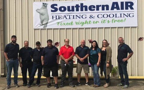 Southern Air Heating & Cooling team members standing in front of company building with logo and mascot bear sign.
