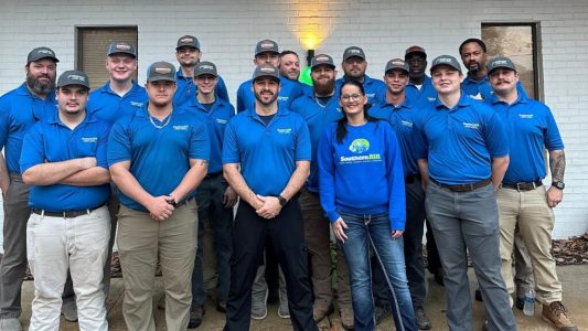 Professional team of HVAC, plumbing, and electrical technicians in blue uniforms posing together at Shreveport location.